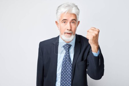 Photo for Portrait of an elderly angry boss screams and threatens with his fist on white background - Royalty Free Image