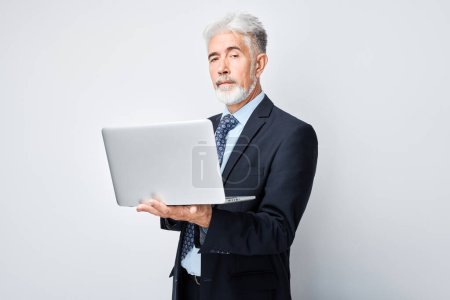 Téléchargez les photos : Homme d'affaires senior utilisant un ordinateur portable sur fond blanc. - en image libre de droit