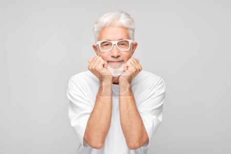 Téléchargez les photos : Portrait d'un homme âgé souriant aux cheveux blancs et à la barbe posant sur un fond gris. - en image libre de droit