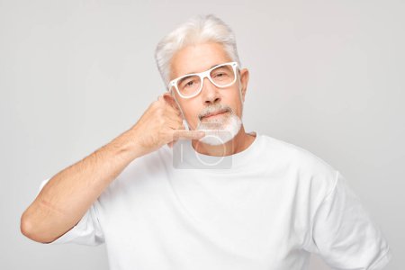 Téléchargez les photos : Homme âgé confiant avec des lunettes faisant appel à moi geste sur fond gris. - en image libre de droit
