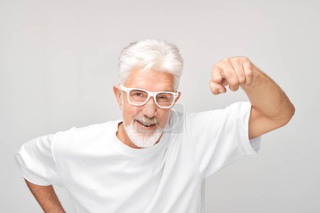 Foto de Hombre mayor enojado con gafas apuntando a la cámara, aislado sobre fondo blanco. - Imagen libre de derechos