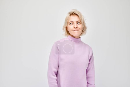 Téléchargez les photos : Portrait d'une jeune femme réfléchie au col roulé violet, isolée sur fond blanc. - en image libre de droit