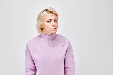 Téléchargez les photos : Portrait d'une femme coûteuse au col roulé violet regardant sur le côté sur un fond gris. - en image libre de droit