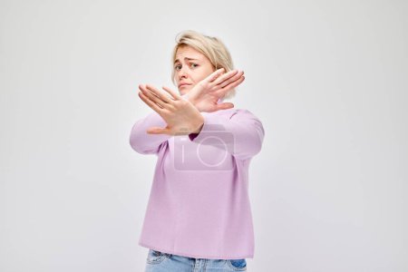 Photo for Woman in pink top making stop gesture with crossed arms on white background. - Royalty Free Image