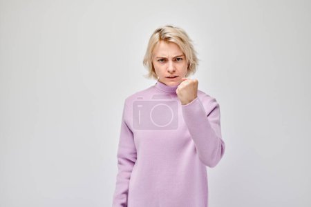 Photo for Angry woman in a purple sweater clenching her fists isolated on a white background. - Royalty Free Image