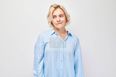 Téléchargez les photos : Portrait de femme souriante en chemise bleue sur fond blanc, exprimant positivité et confiance. - en image libre de droit