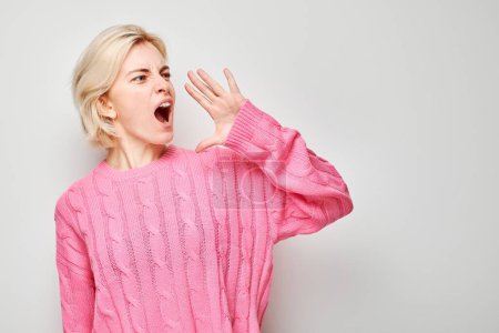 Portrait of blonde girl shouting loudly with hands, news, palms folded like megaphone isolated on white background