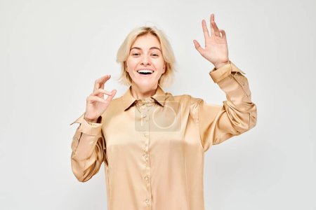 Portrait blond young woman happy face smiling joyfully with raised palms and shocked open mouth isolated on white studio backgroun