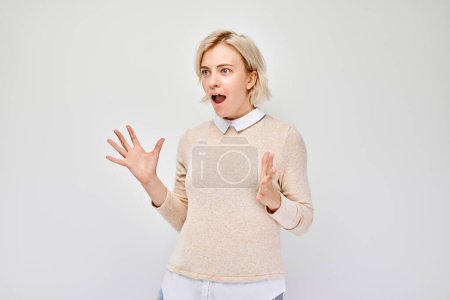 Portrait blond young woman happy face smiling joyfully with raised palms and shocked open mouth isolated on white studio backgroun