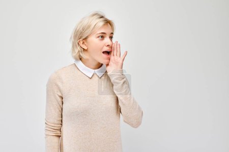 Photo for Portrait of blonde girl shouting loudly with hands, news, palms folded like megaphone isolated on white background - Royalty Free Image