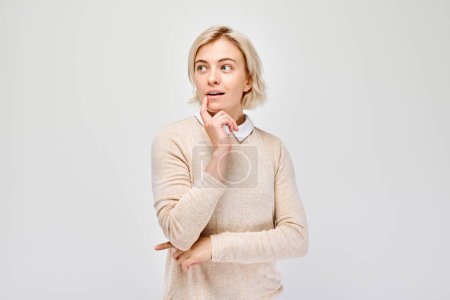 Téléchargez les photos : Femme pensive avec la main sur le menton regardant loin, isolé sur fond blanc. - en image libre de droit