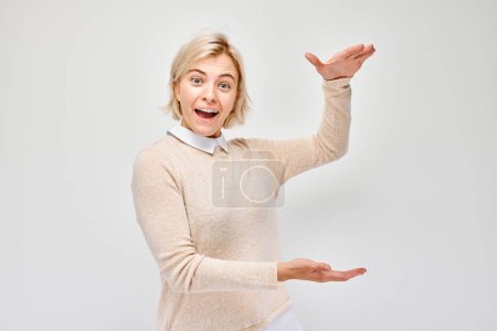 Téléchargez les photos : Femme excitée gestuelle avec les mains, montrant la taille, sur fond blanc. - en image libre de droit