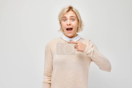 Photo for Surprised woman pointing at copy space with a funny expression, isolated on a light background. - Royalty Free Image