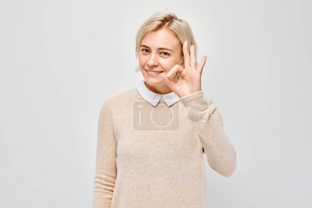Téléchargez les photos : Femme souriante faisant un geste correct, isolée sur fond de lumière. - en image libre de droit
