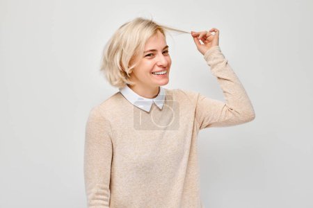 Téléchargez les photos : Portrait de femme blonde tenant sa mèche de cheveux, insatisfaite de la qualité des cheveux, pointes sèches et fourchues - en image libre de droit