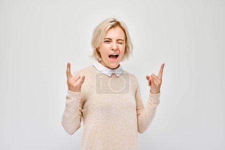 Excited young woman gesturing rock on sign with both hands, expressing joy and enthusiasm, isolated on white background.
