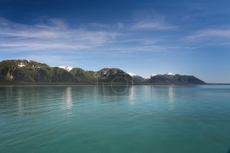 Serene alaskan landscape on a sunny day with turquoise water and blue sky