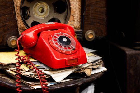 Foto de Teléfono antiguo rojo, antiguo entre viejas radios y papeles - Imagen libre de derechos