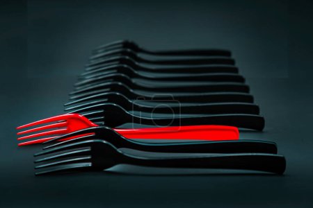 Téléchargez les photos : L'étrange fourchette rouge entre les fourchettes noires - en image libre de droit