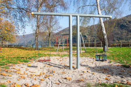 Empty playground for children near the river. Swings, sands for play in autumn time.