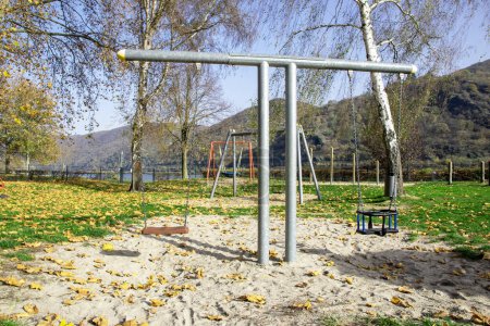 Empty playground for children near the river. Swings, sands for play in autumn time.