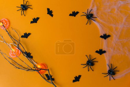 Halloween decorations with pumpkins, bats, web, bugs on orange background. Party greeting card with copy space. 