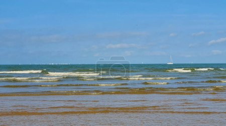 Foto de Hermoso mar con arena, yates, olas en el agua y el cielo azul. Fondo natural para vacaciones de verano. - Imagen libre de derechos
