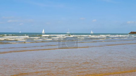 Foto de Hermoso mar con arena, yate, olas en el agua y cielo azul. Fondo natural para vacaciones de verano. - Imagen libre de derechos