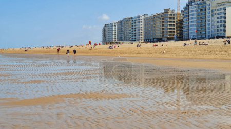 Foto de Gente caminando por la playa de arena cerca del mar con muchas casas y hotel por la noche. - Imagen libre de derechos