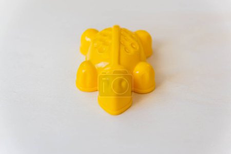 Little toy on the wood background. Yellow plastic turtle on the beige table. 