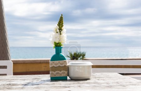 Warehouse on the open air. Chairs and tables outside on the summer sun weather. Vase with the flowers on the table for summer cafe with sea view.