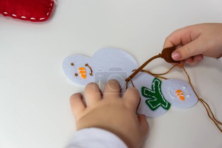 The hand of the child make snowman for christmas greeting card. Hobby concept. Handmade.