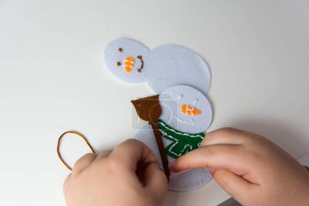 The hand of the child make snowman for christmas greeting card. Hobby concept. Handmade.