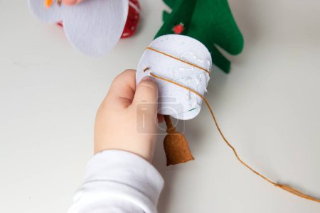 La mano del niño hace muñeco de nieve para la tarjeta de felicitación de Navidad. Decoración de juguetes de Navidad para tarjeta de felicitación. Feliz Navidad y Feliz Año Nuevo decoración. Concepto hecho a mano.