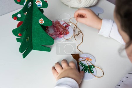 Die Hand des Kindes machen Schneemann und Weihnachtsbaum für Weihnachtsgrußkarte. Weihnachtsspielzeug Dekoration für Grußkarte. Frohe Weihnachten und einen guten Rutsch ins neue Jahr. Handgemachtes Konzept.