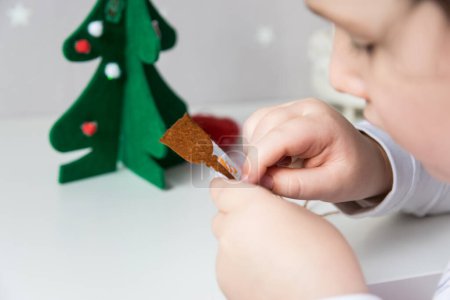 Die Hand des Kindes bastelt Schneemann und Christbaum für die Weihnachtsgrußkarte. Weihnachtsspielzeug Dekoration für Grußkarte. Frohe Weihnachten und einen guten Rutsch ins neue Jahr. Handgemachtes Konzept.