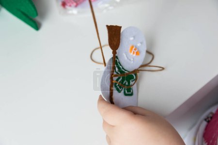La mano del niño hace muñeco de nieve para la tarjeta de felicitación de Navidad. Decoración de juguetes de Navidad para tarjeta de felicitación. Feliz Navidad y Feliz Año Nuevo decoración. Concepto hecho a mano.
