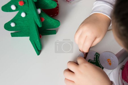 Die Hand des Kindes machen Schneemann und Weihnachtsbaum mit Nadel, Faden für Weihnachtsgrußkarte. Hobby Konzept. Handgefertigt.