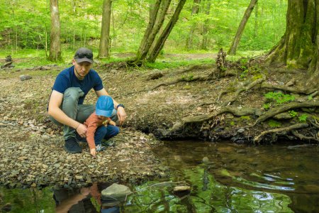 Dad with son toddler hiking together at sping forest near the river. . High quality photo