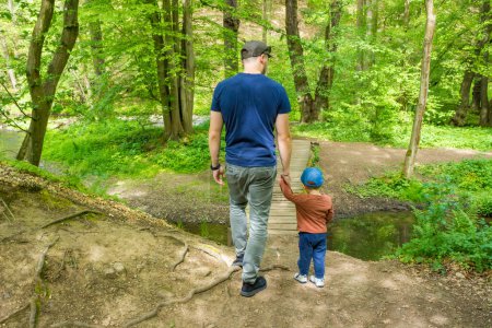 Dad with son toddler hiking together at sping forest near the river. . High quality photo
