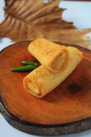 Sosis Solo stuffed with minced meat or shredded chicken is ready to be served with green cayenne pepper on a circle of wooden boards in Semarang, Indonesia on March 27, 2021.