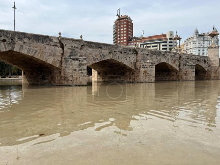 Dieses Bild zeigt eine malerische historische Steinbrücke, die sich anmutig über einen ruhigen Fluss spannt. Die Brücken alten Steinbögen und stabile Konstruktion evozieren ein Gefühl von zeitloser Schönheit und