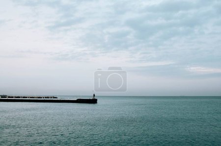 a man walks along a wooden pier that leads into the Black Sea in Odessa. High quality photo