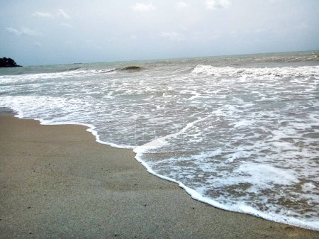 Kleine Wellen an der weißen Küste am Strand