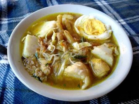 traditionelle indonesische Küche. Soto Ceker Ayam Kuah Kuning Dengan Ketupat oder Soto Hühnerfüße. Soto Ceker Ayam Kuah Kuning Indonesisches Essen, das einfach ist und oft zu Hause zubereitet wird.