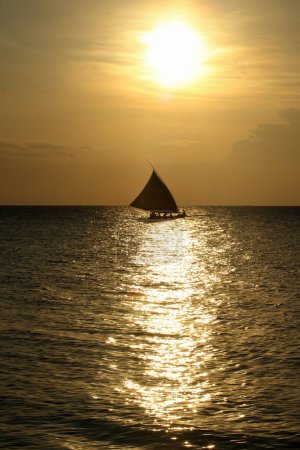 Silhouette eines Fischerbootes mit ausgestreckten Segeln. Hintergrund Sonnenuntergang. Der Himmel ist orange