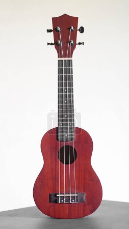 Four stringed ukulele guitar made of wood on a white background