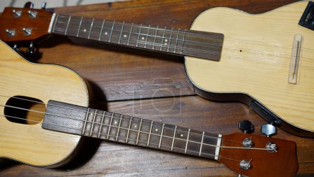 Téléchargez les photos : Four stringed ukulele guitar made of wood on a wooden table. Focus selected - en image libre de droit