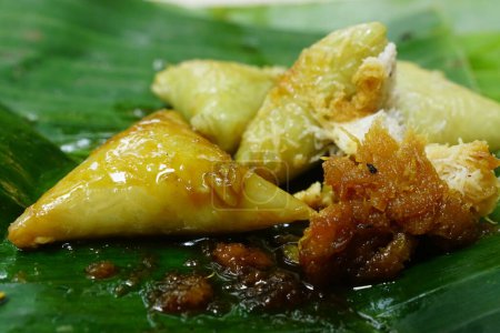 Lupis, a traditional cake from Java Indonesia. Made from rice, given grated coconut and brown sugar liquid. Served on banana leaves. Focus selected