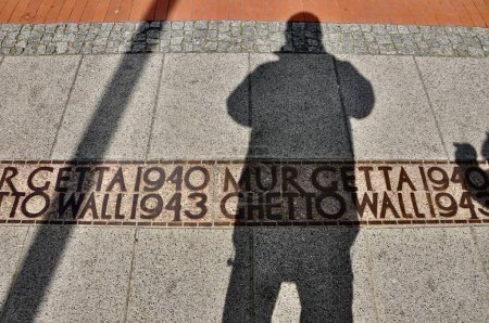 Mi sombra sobre el memorial del guetto de Varsovia en las calles caminando hacia los restos del muro.